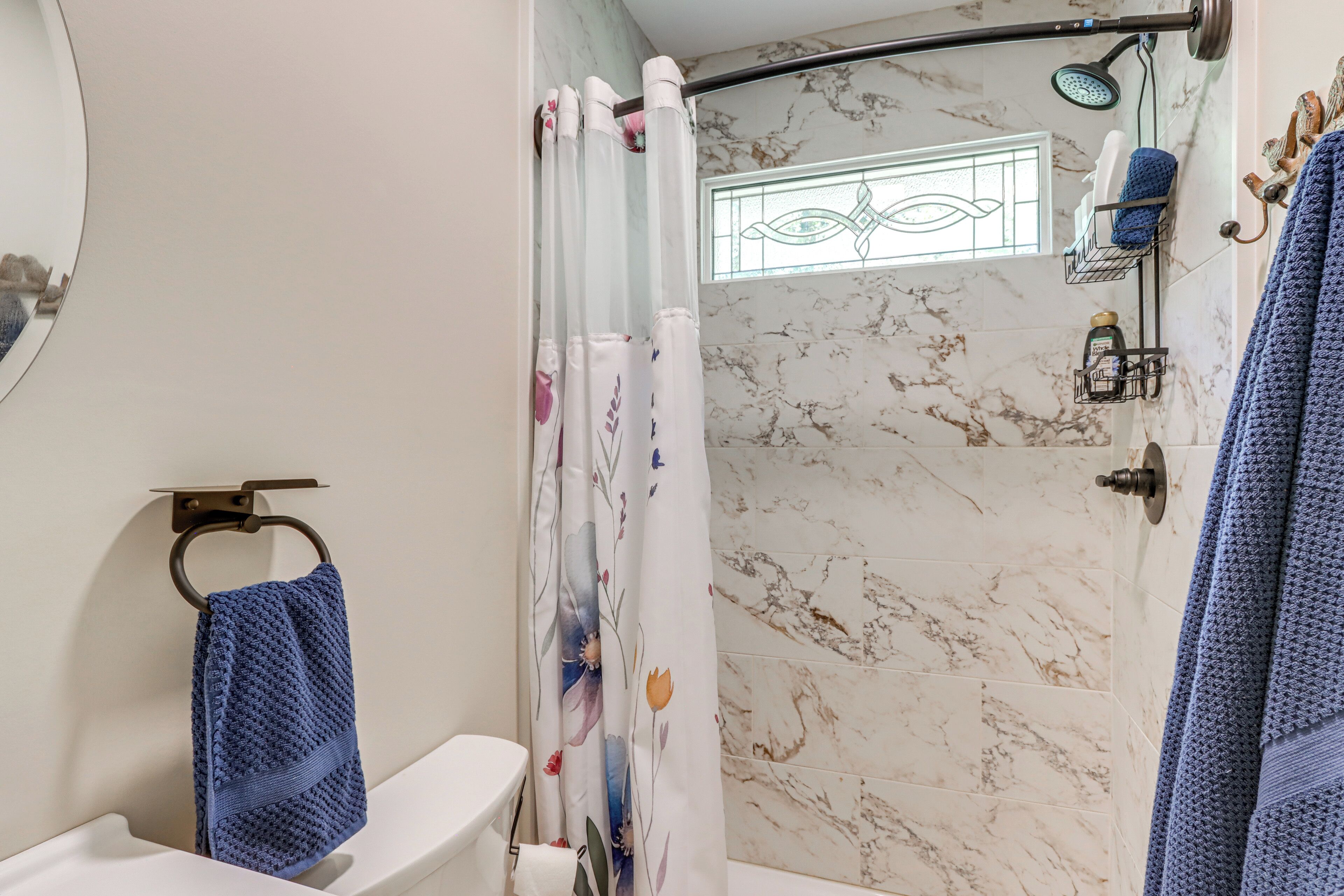 A bathroom with a shower, toilet, and a towel rack.
