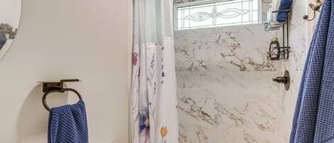 A bathroom with a shower, toilet, and a towel rack.