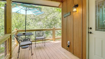 A wooden deck with a table and chairs, a door with a sign, and a lantern.