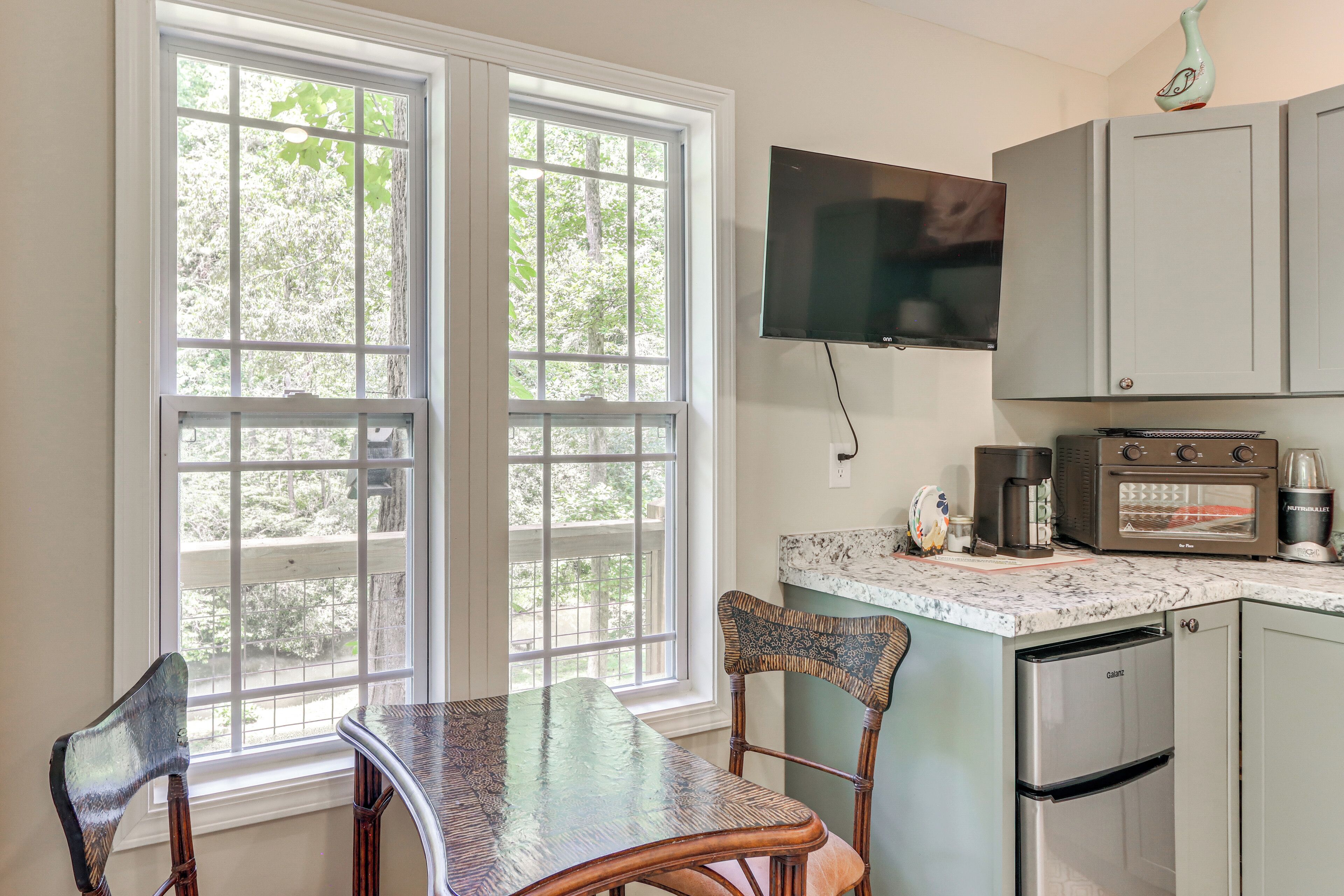 A kitchen with a dining table, chairs, a television, and a coffee maker.