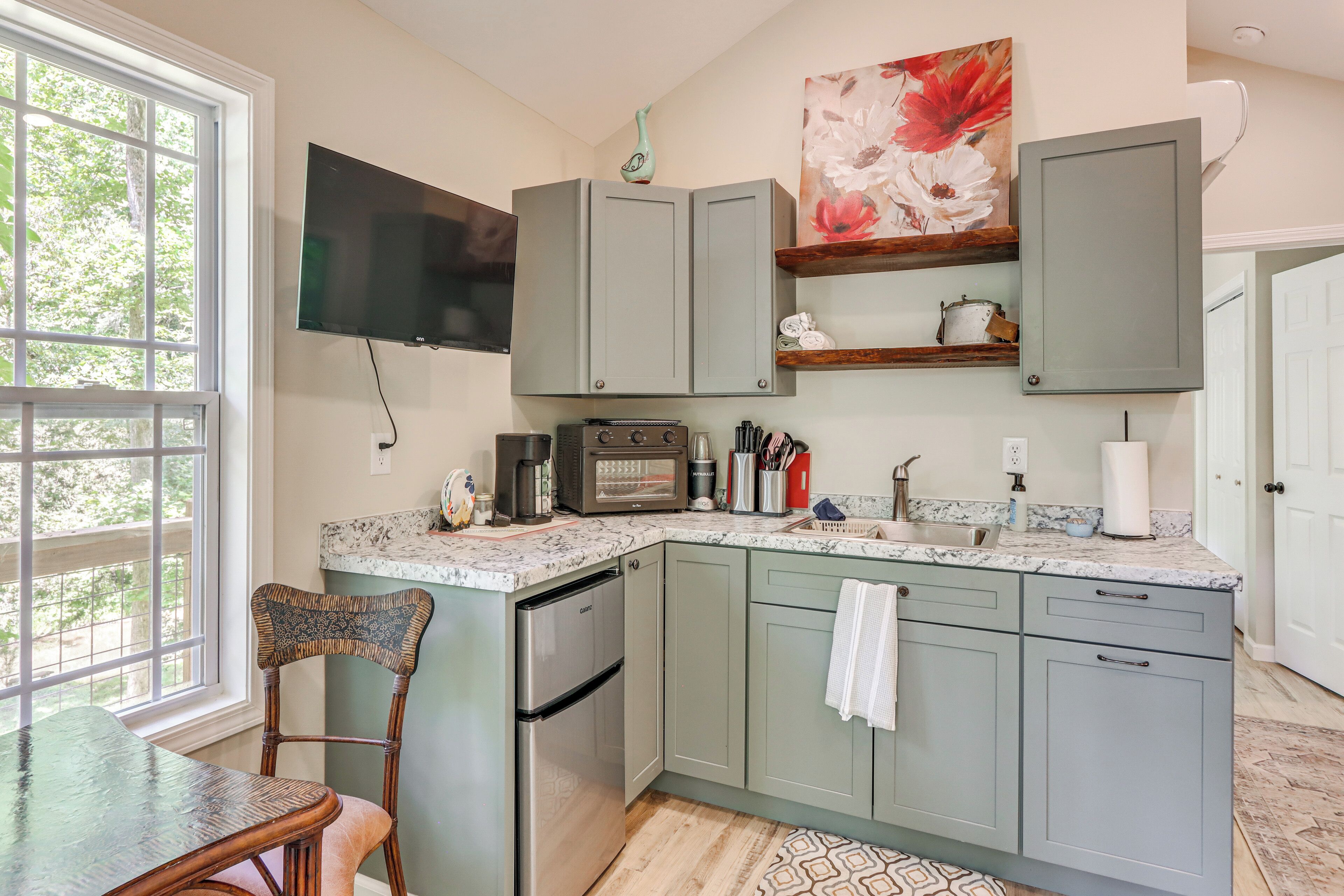 A kitchen with a built-in oven, a coffee maker, and a flat-screen TV mounted above the counter.