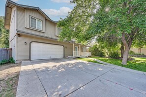 A two-story house with a garage, a front porch, and a large tree in the yard.