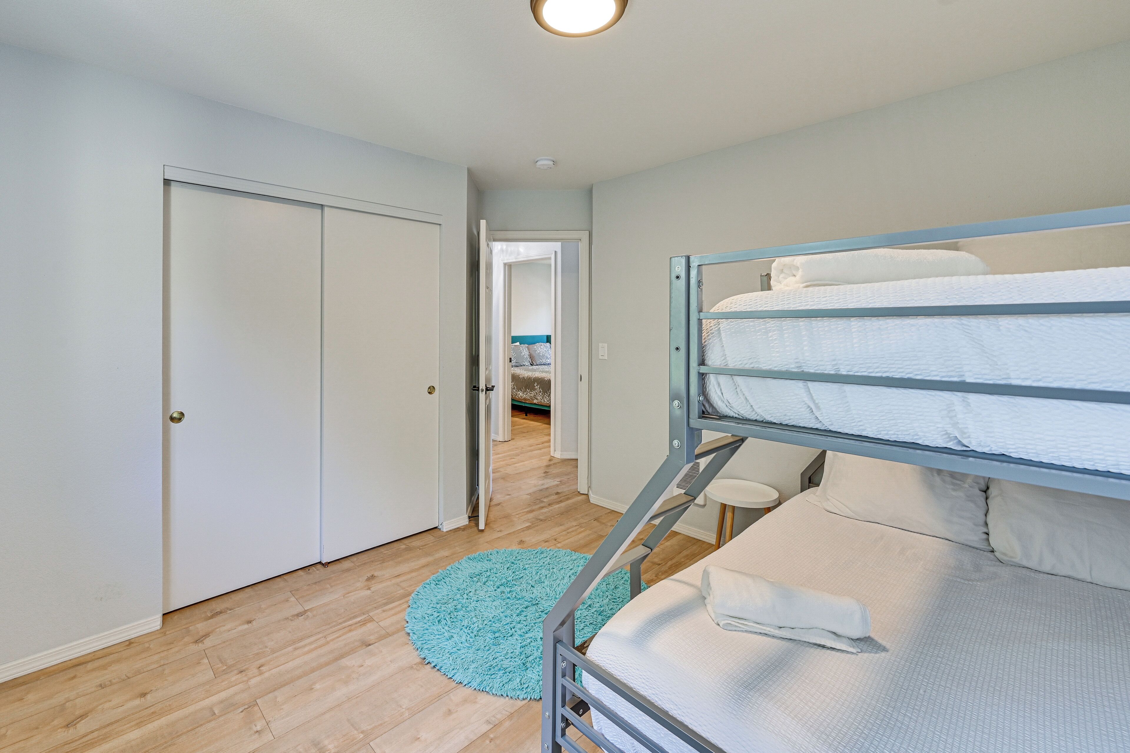 A bunk bed with a blue metal frame, a white door, and a wooden floor.