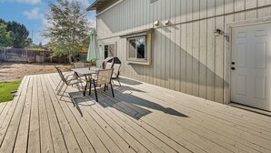 A wooden deck with a table and chairs, a white door, and a window.