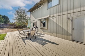 A wooden deck with a table and chairs, a white door, and a window.