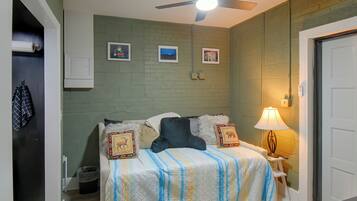 A bedroom with a bed, a nightstand with a lamp, and a ceiling fan.