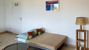 Ein Zimmer mit einem Bett, einem Sessel, einer Lampe, einer Klimaanlage und einer Tür.