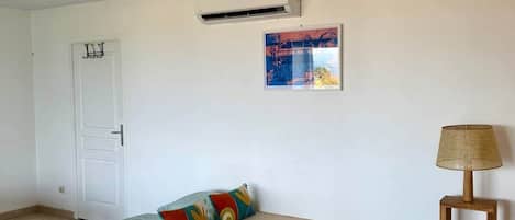Una habitación con cama, una silla, una lámpara, aire acondicionado y una puerta.