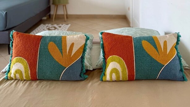 Ein Zimmer mit einer Couch, einem kleinen Beistelltisch und zwei Zierkissen.