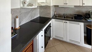Eine Küche mit weißen Schränken, einer schwarzen Arbeitsplatte und einer Marmor-Spritzschutzwand.