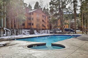 A swimming pool with a surrounding deck, a fenced area, and a building in the background. - Steps to the Slopes! Breck Ski Condo w/ Fireplace (Breckenridge)