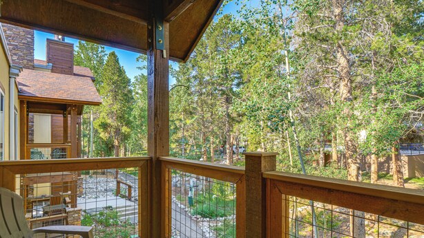 Eine Holzterrasse mit Blick auf ein Steinhaus und einen bewaldeten Bereich.