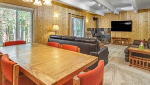 Ein geräumiges Wohnzimmer mit einem Holzesstisch, einer Ledersofa und einem an der Wand montierten Flachbildfernseher.