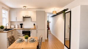 Una cocina moderna con armarios blancos, una mesa de comedor de madera y un espejo con marco negro.