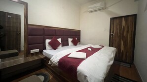 Habitación de hotel con cama, cabecera de madera, espejo, equipo de aire acondicionado y puerta.