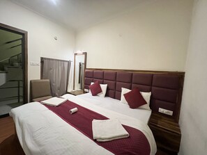 A hotel room with a large bed, a chair, a mirror, and a door leading to a staircase. - OnlyStay Bagpackers Hostel (Agra)