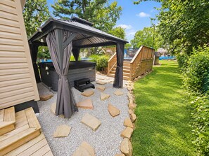 A covered outdoor seating area with a grill, stone pathway, and wooden deck. - The Oasis of Massillon Pet Friendly + Pool + Fenced in Back Yard (Massillon)