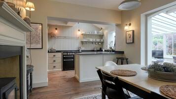 A modern kitchen with a central island, wooden flooring, and a dining area with a table and chairs.