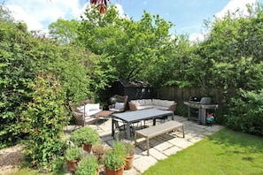 Un espace extérieur aménagé avec une terrasse, des sièges, un barbecue et des plantes en pot.