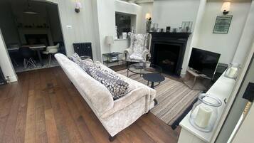 A living room with a sofa, a fireplace, a television, and a dining area.