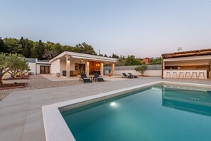 A modern outdoor pool area with a covered patio, lounge chairs, and a clear blue pool. - Villa Casa Olea Zadarvillas (Benkovac)