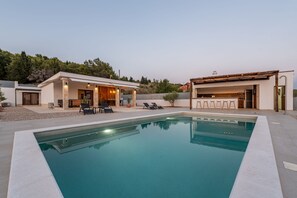 A modern poolside area with a rectangular pool, outdoor seating, and a covered patio. - Villa Casa Olea Zadarvillas (Benkovac)