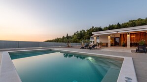 Ein moderner Pool mit klarer, blauer Wasseroberfläche, umgeben von einer Betonplattform.