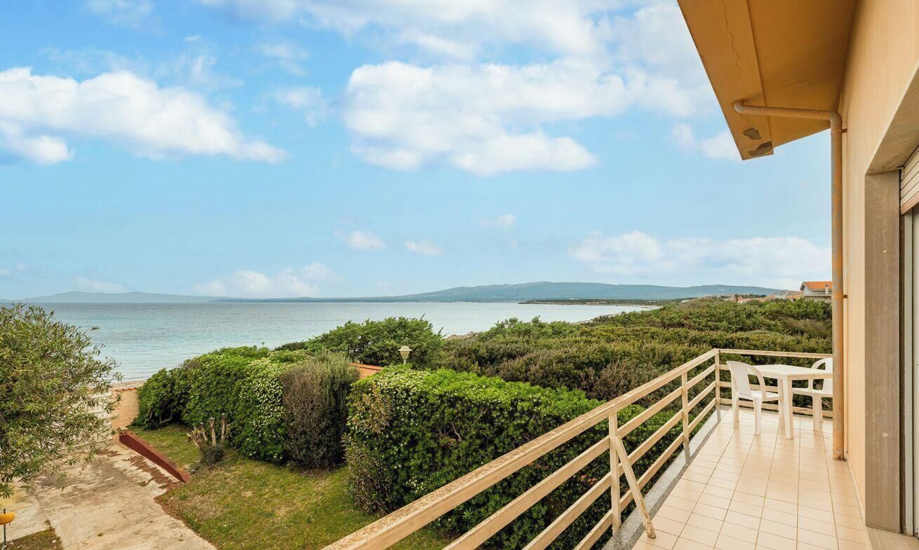 Uma varanda com vista para o mar e um caminho no jardim que leva ao mar.