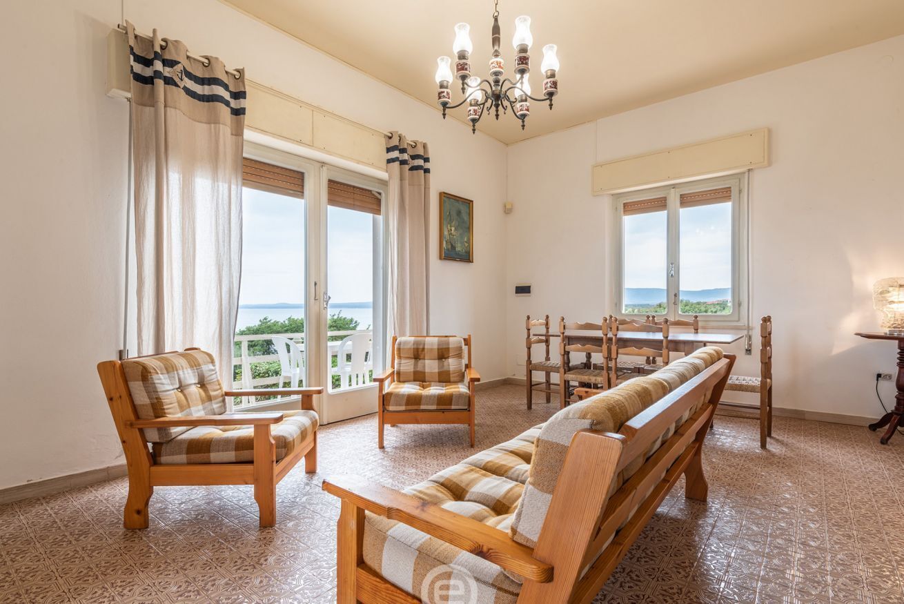 Ein geräumiges Wohnzimmer mit großem Fenster, Essbereich und Blick ins Freie.