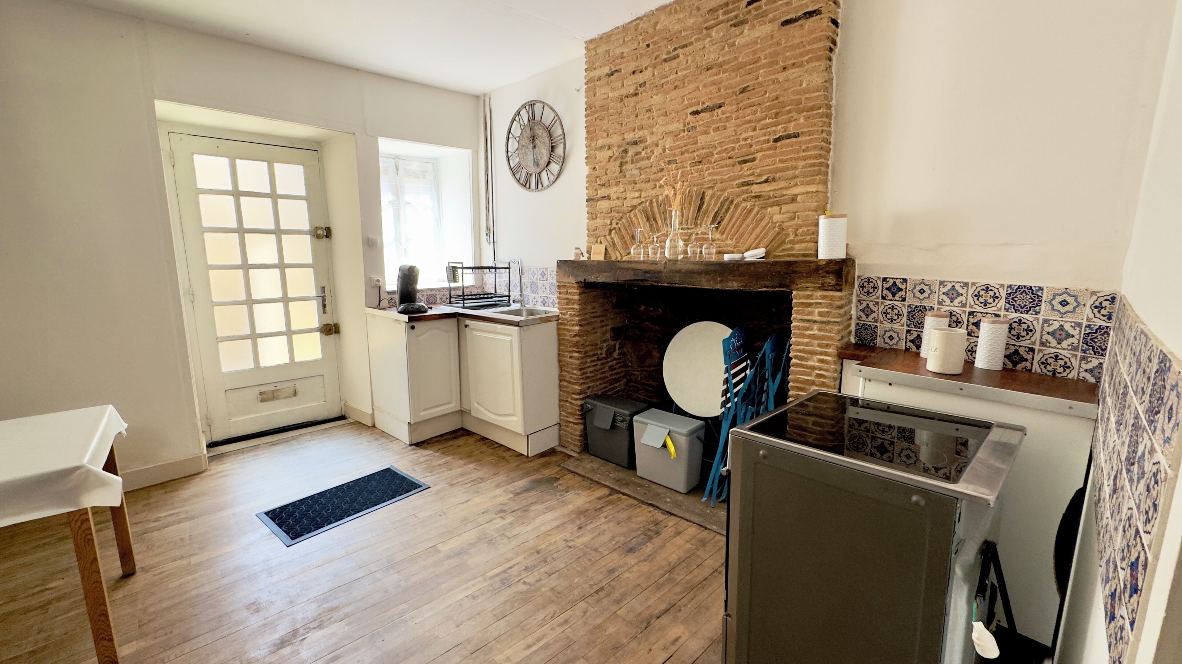 Una cocina compacta con pared de ladrillo, un lavamanos, una estufa y un refrigerador.