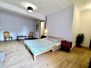 Een slaapkamer met een houten bed, twee nachtkastjes, een stoel en een kamerplant.