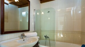Een badkamer met een wastafel, spiegel en douche.