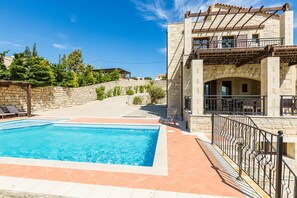 Une piscine avec un mur en pierre et une pergola.