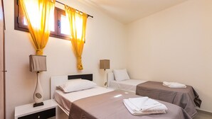 Een hotelkamer met twee eenpersoonsbedden, een nachtkastje met een lamp en een raam met gordijnen.
