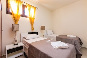 A hotel room with two single beds, a nightstand with a lamp, and a window with curtains. - Thalia, Traditional Stone Villa, Intimate Spaces & Private Pool, Family Friendly (Lefkogeia)
