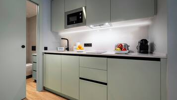Una cocina moderna con microondas incorporado, cafetera y frutero en la encimera.