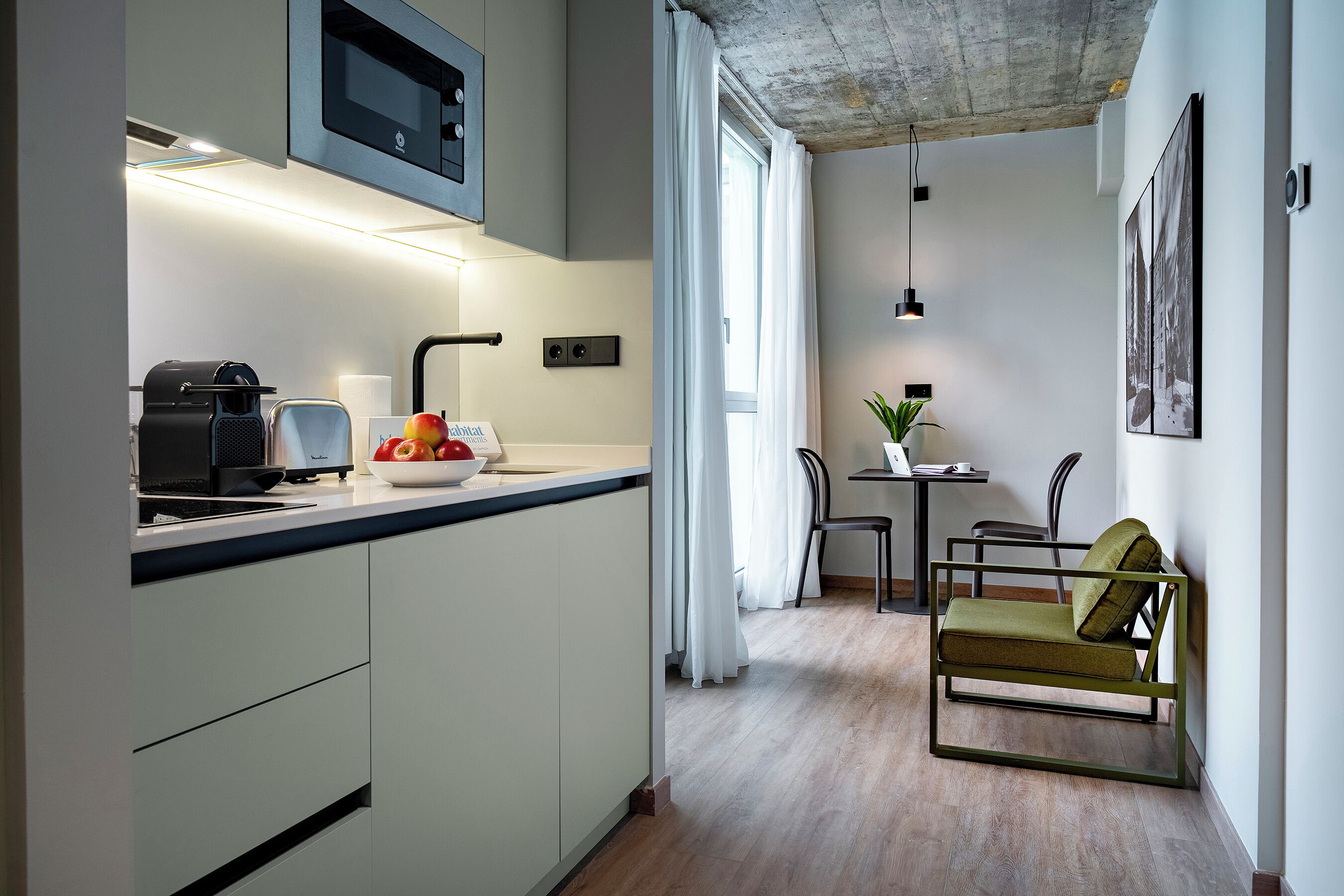 A modern kitchen with a built-in oven, a coffee machine, and a bowl of fruit on the counter.