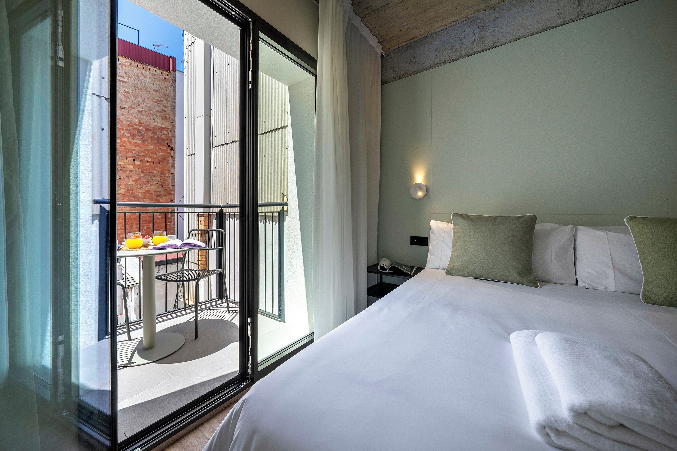 Ein Hotelzimmer mit Bett, einem Tisch mit Frühstücksangeboten und Blick auf ein Gebäude.