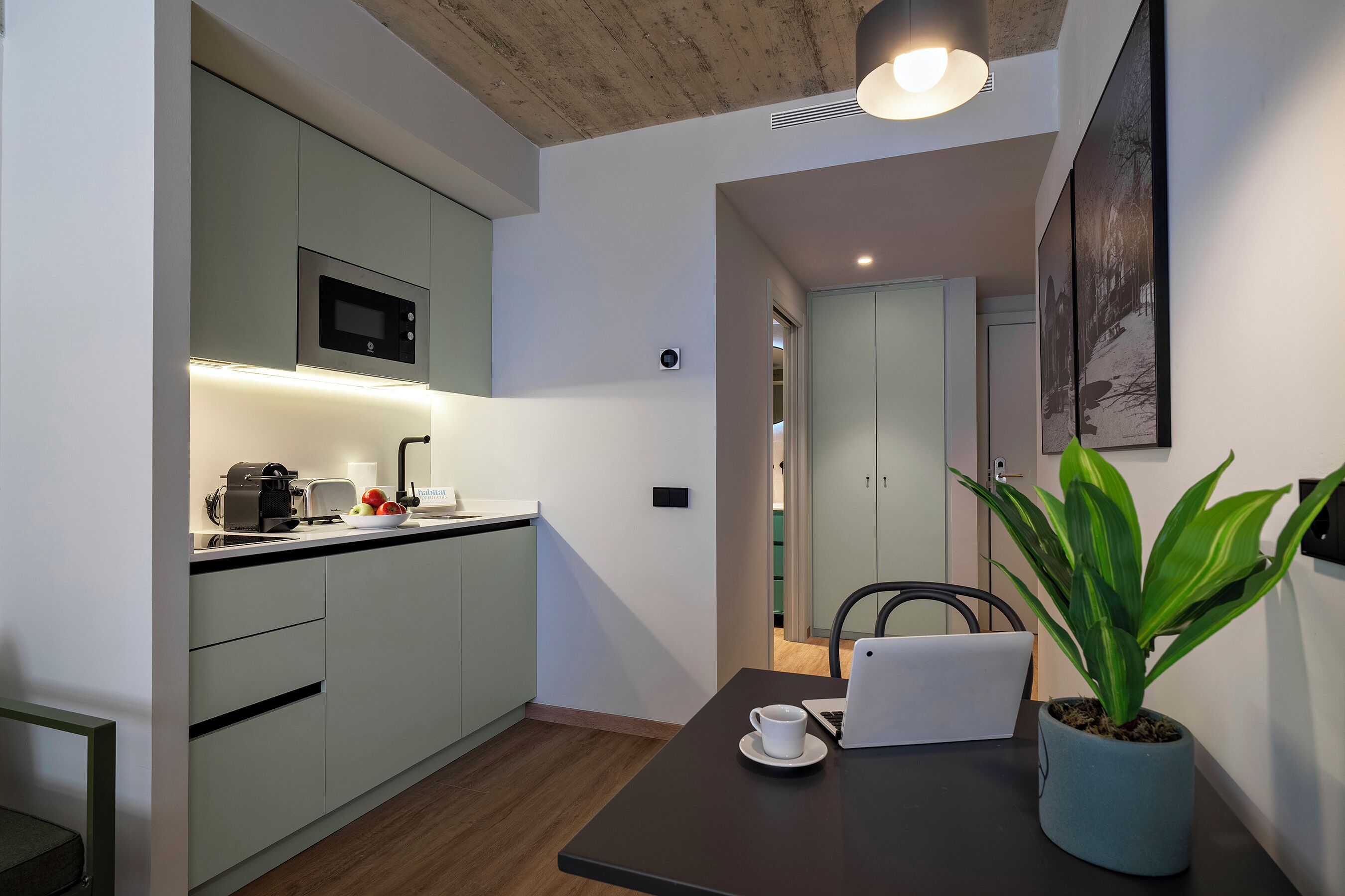 A modern kitchen with a built-in microwave, toaster, and a bowl of fruit on the counter.