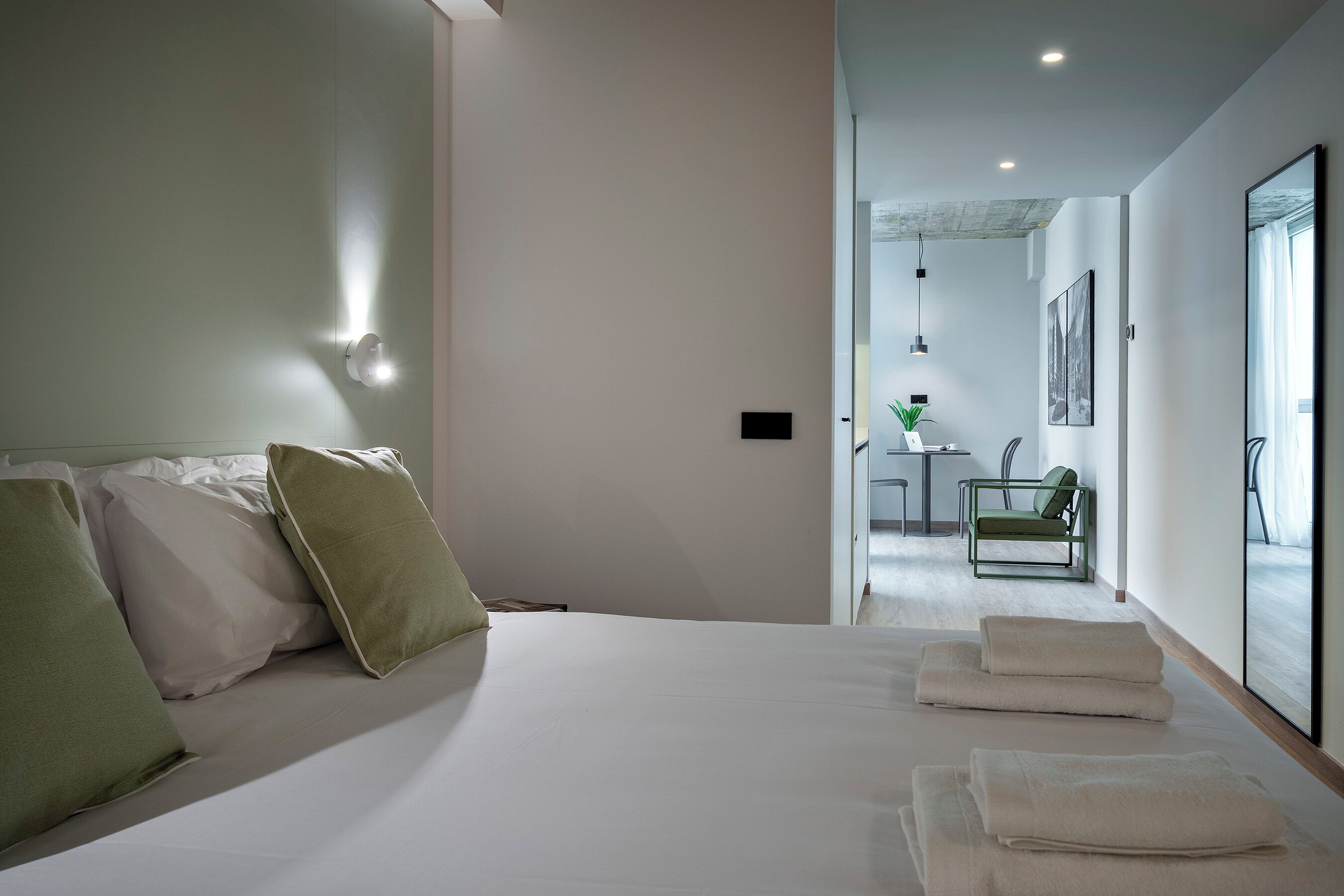 Een moderne hotelkamer met een bed, kussens, een bureau en een stoel.