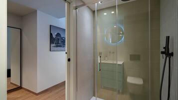 Un baño moderno con ducha de vidrio, inodoro y lavamanos.