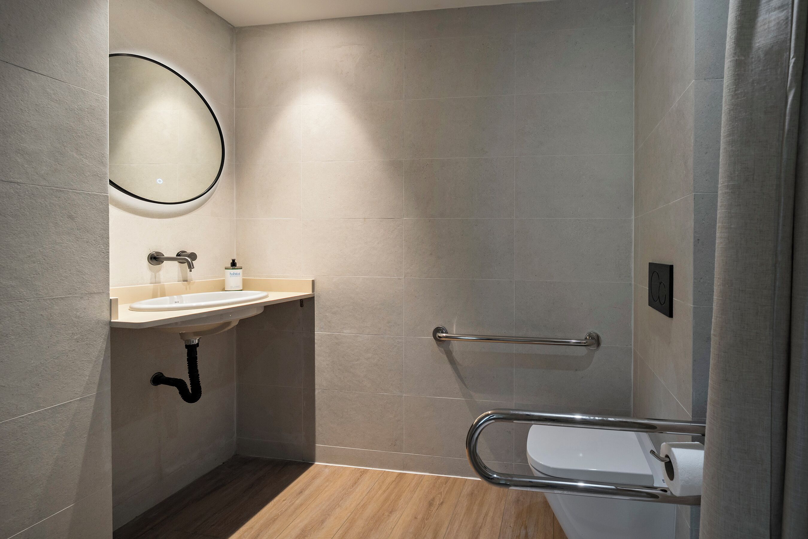 Un baño moderno con lavamanos, espejo y retrete.