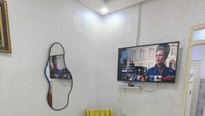 A living room with two yellow armchairs, a small coffee table, a flat-screen TV mounted on the wall, and a framed picture. - Mydar medina (Tanger)