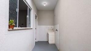 En smal hall med ett fönster på vänster sida, en dörr längst ner och en liten tvätthörna med ett skåp.
