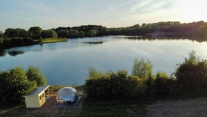 A lakeside view with a transparent dome structure and a small building. - The Most Beautiful Way | To Say | "I Love You" (Wadersloh)