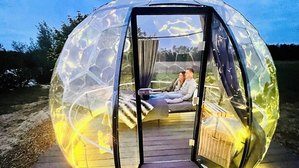 A spherical transparent structure with a wooden deck and a bed inside. - The Most Beautiful Way | To Say | "I Love You" (Wadersloh)