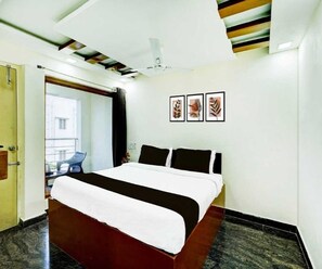 A hotel room with a bed, a ceiling fan, and three framed pictures on the wall.