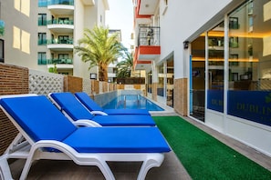 Una piscina al aire libre, camas de piscina gratis, sombrillas