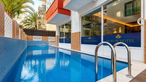 En swimmingpool med en klar, blå vandoverflade, omgivet af et bassin med flisebelagte omgivelser.