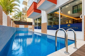 A swimming pool with a clear blue water surface, surrounded by a poolside area with a tiled deck. - Dublin Hotel  (Alanya)